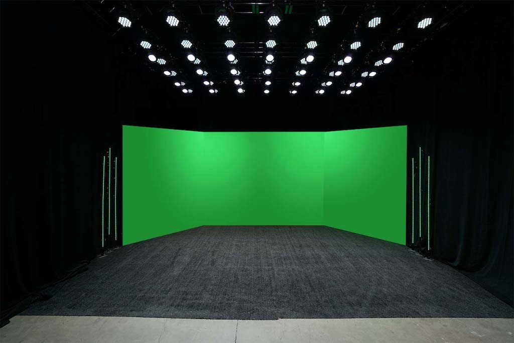 green screen in a black room with rows of lights on top